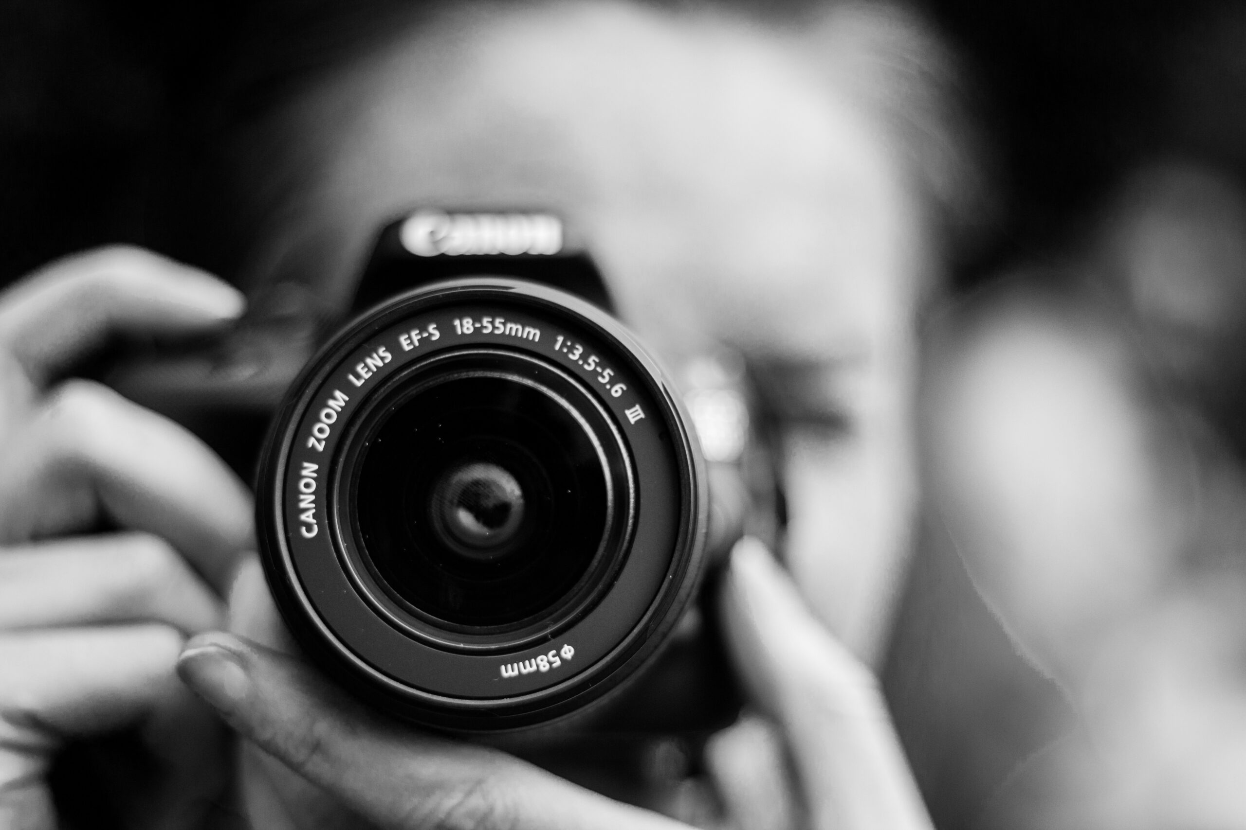 A black and white photo of a photographer holding a camera up to capture the shot